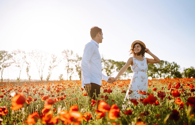 Loving couple in the poppy field at sunset Enjoying time together love and lifestyle