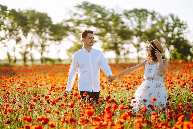 Loving couple in the poppy field at sunset Enjoying time together love and lifestyle