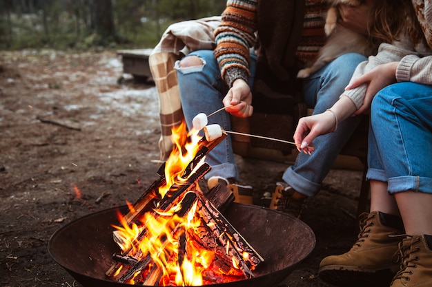 Loving couple prepares marshmallows by the fire. Autumn forest,