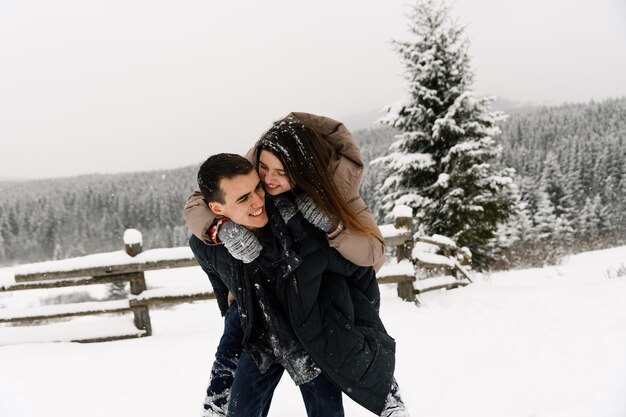 Loving couple in puffer jacket on a winter walk. Man and woman having fun in the frosty forest. Romantic date in winter time.Christmas mood of a young family.Winter lovestory