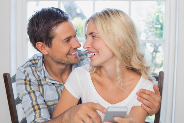 Loving couple reading text message together at home