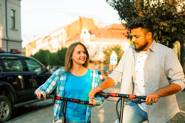 The loving couple ride an electric scooters and look at each other