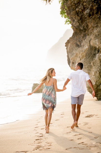 Loving couple running on sunny sea beach