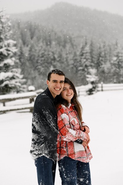 Влюбленная пара в рубашке на зимней прогулке. Мужчина и женщина веселятся в морозном лесу. Романтическое свидание зимой. Новогоднее настроение молодой семьи. Зимняя любовная история.