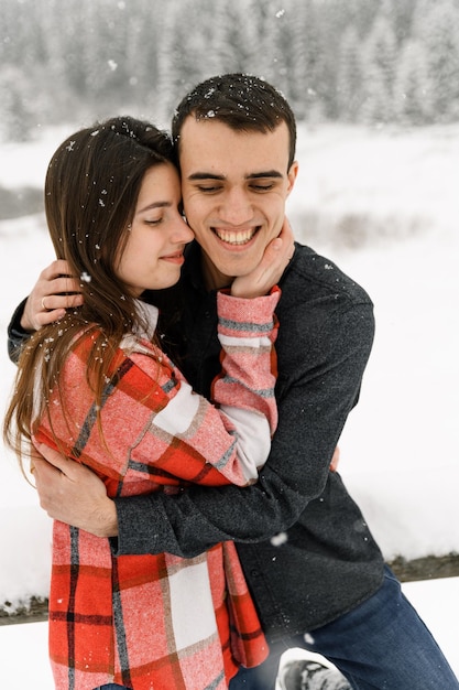 Loving couple in shirt on a winter walk. Man and woman having fun in the frosty forest. Romantic date in winter time.Christmas mood of a young family.Winter lovestory