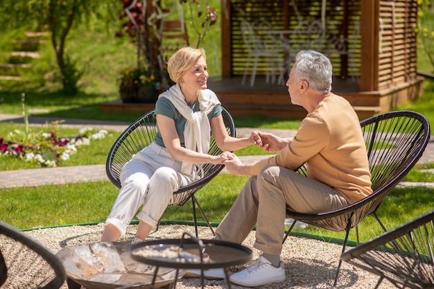 Loving couple sitting in the arm-chairs in the garden