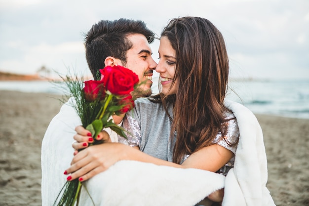 Photo loving couple sitting on a beach with a bouquet of roses