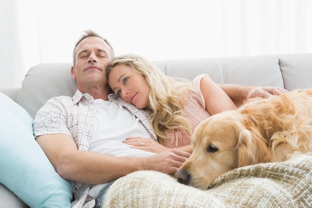 Loving couple sitting on couch with their dog