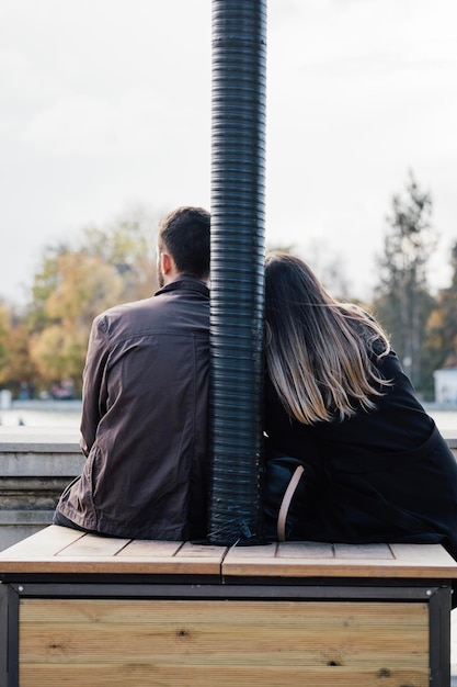 Loving couple sitting in front of lake view Rear view Man and woman traveling together Traveler couple enjoying nature embracing watching landscape together Copy space