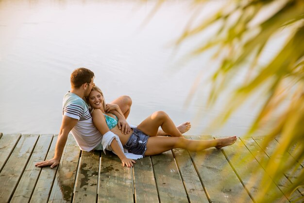 Loving couple sitting on the pier on lake