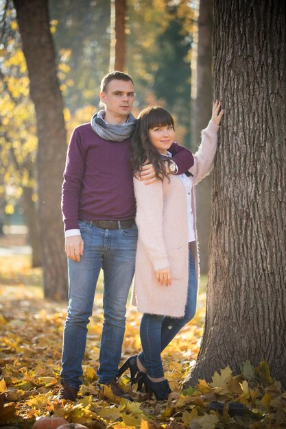 Loving couple stand near a tree in the autumn park