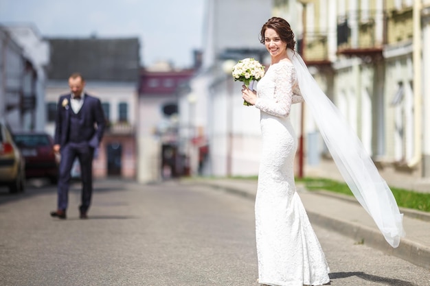 Loving couple of stylish newlyweds walks and kisses in the old city in summer sunny day