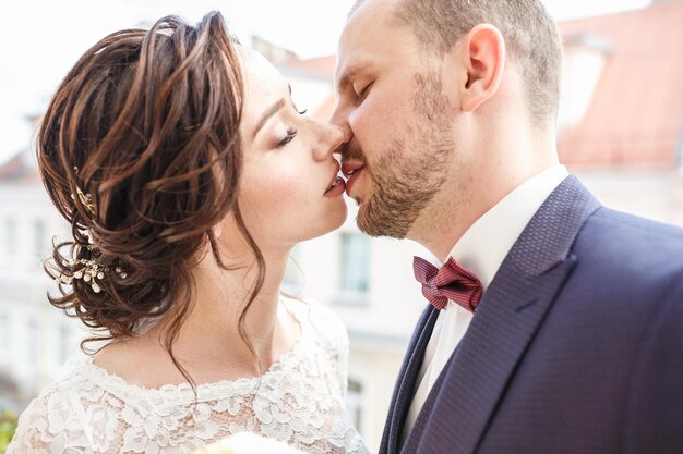 Loving couple of stylish newlyweds walks and kisses in the old city in summer sunny day