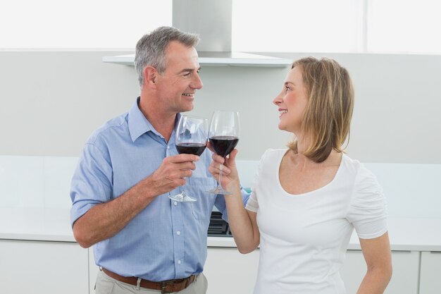 Loving couple toasting wine glasses in kitchen