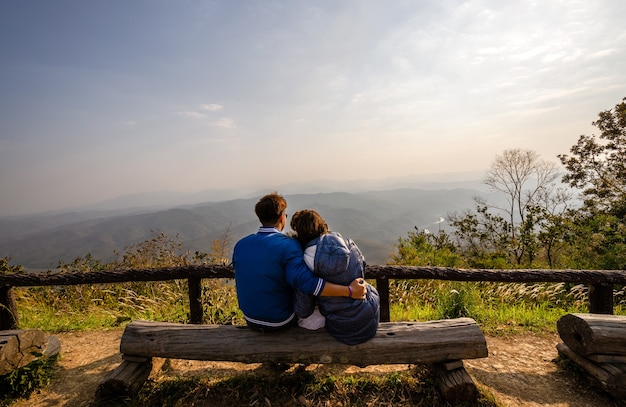 Loving couple travelers Man and Woman sitting on cliff mountains, love and travel happy emotions lifestyle family concept, Doi Samer Dao, Nan Province, Thailand.