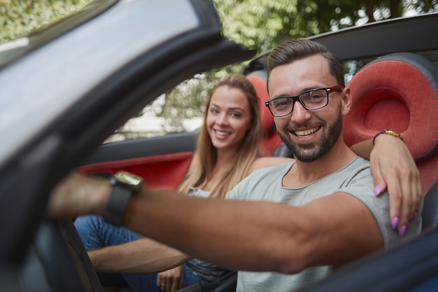 Loving couple traveling in a convertible car