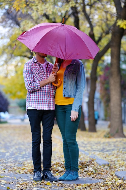 Loving couple under an umbrella in autumn park