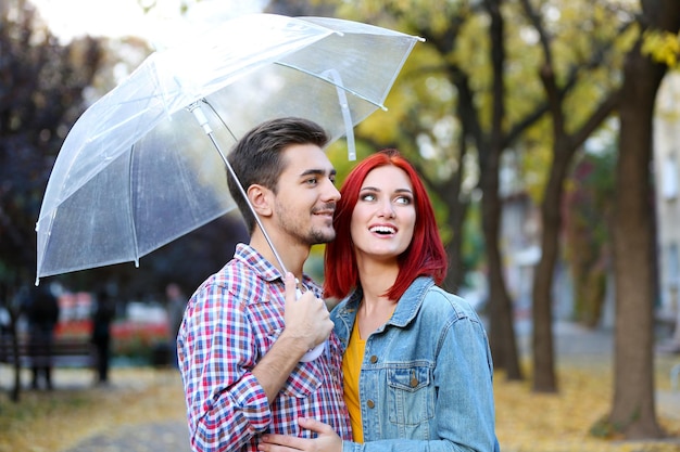 Loving couple under an umbrella in autumn park