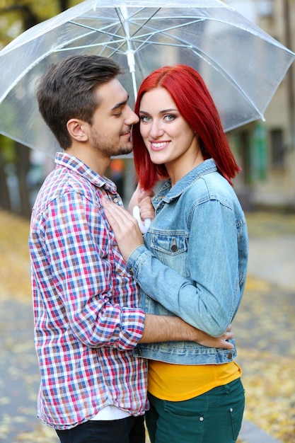 Loving couple under an umbrella in autumn park