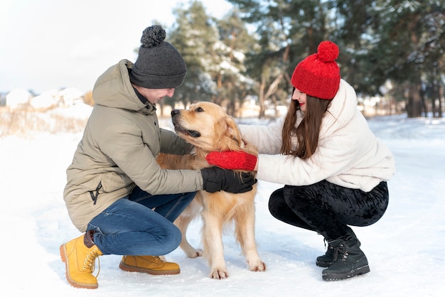 愛するカップルは犬と一緒に冬の森を歩きます。幸せな若い家族。