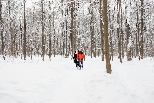 A loving couple walking in winter park. It's snowing, winter.