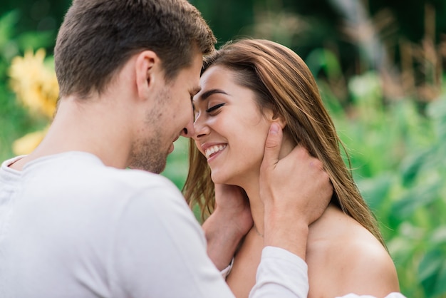 Loving couple in white clothes posing in a field of sunflowers