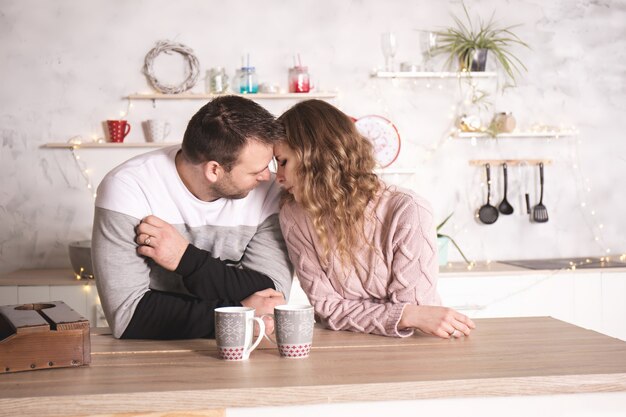 Loving couple in winter clothes in the kitchen