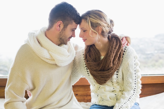 Loving couple in winter clothing against window