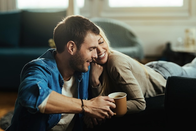 Loving couple with eyes closed sitting close to each other while relaxing in the living room