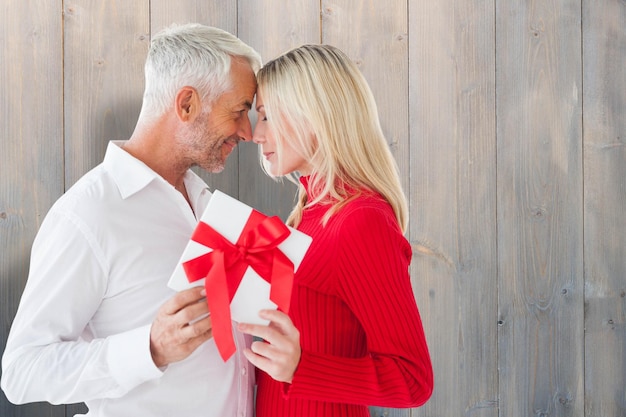 Loving couple with gift against pale grey wooden planks