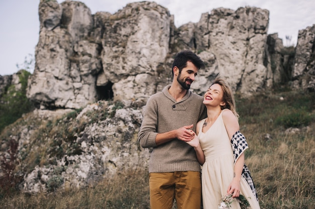 Loving couple wrapped in plaid standing on peak of mountain 