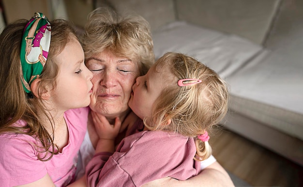 Loving cute granddaughters kissing their grandmother at home