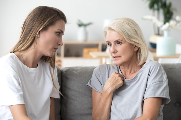 loving daughter comforting consoling aged upset mother at home