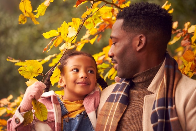 Loving Father Carrying Daughter On Family Walk Through Autumn Countryside Together