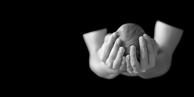 Loving Father holding head of his newborn baby son in hands