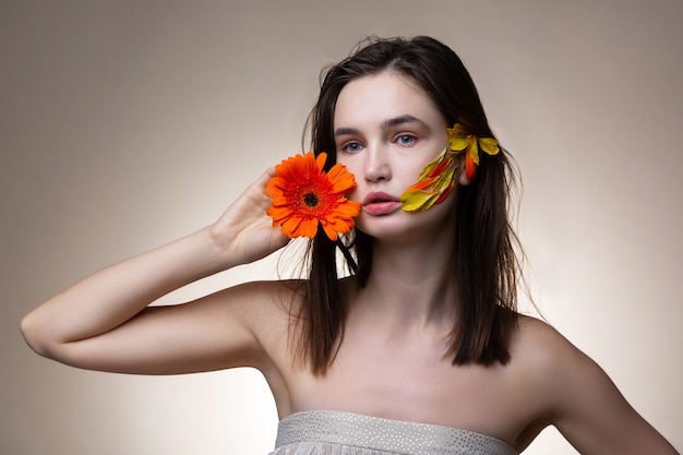 Amare i fiori. giovane attraente donna dai capelli scuri che indossa un vestito a spalla aperta che ama i fiori