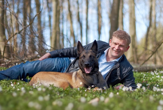 愛する友人男と彼の犬が一緒に森に座っている