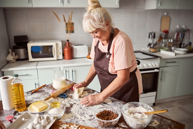 Loving grandma making cookie dough in her kitchen