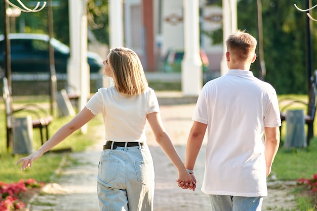 A loving guy and a girl are walking in nature. Lovers walking in the park. Outdoor love story concept.