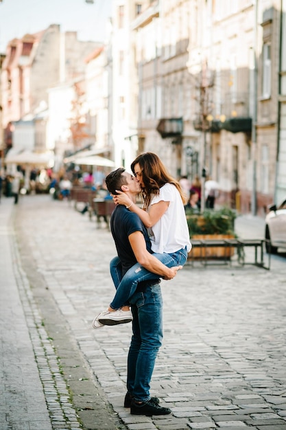 Photo loving happy couple boy kisses girl a man and a woman walking along the streets of the city