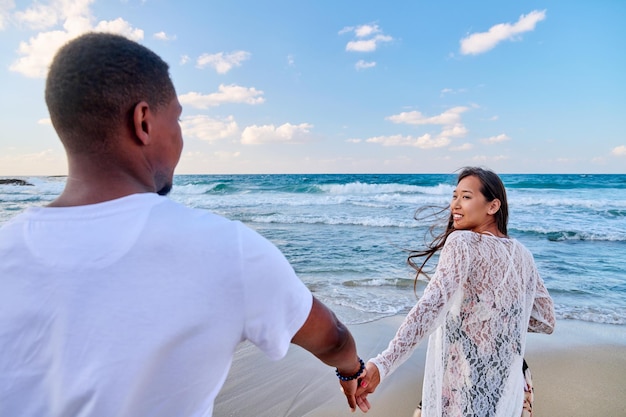 Loving happy couple walking holding hands on the beach