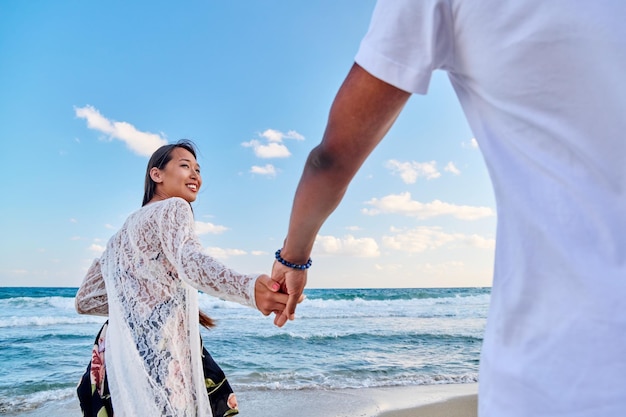 Loving happy couple walking holding hands on the beach