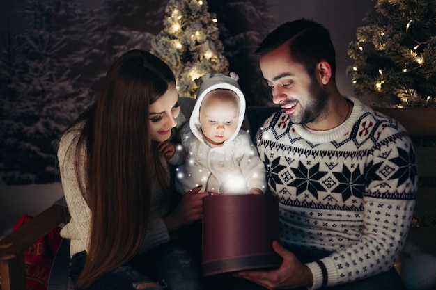 クリスマスプレゼントの中を見ている赤ちゃんと幸せな親を愛する