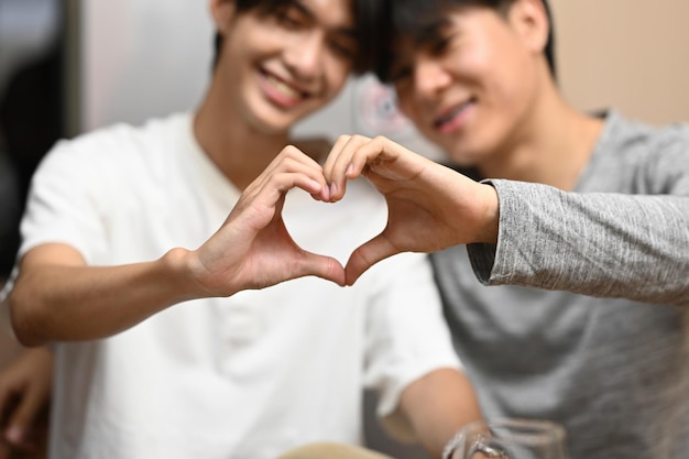 Loving homosexual couple making heart with hands and smiling to camera LGBT relationships and equality concept