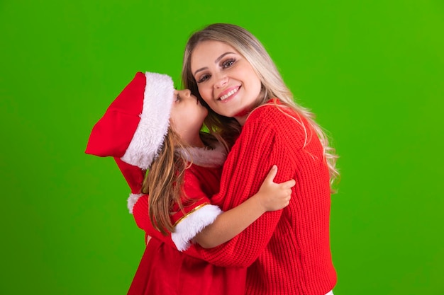 Loving little daughter kisses her hand on her cheek on Christmas night Little girl kisses her mother on the cheek in christmas outfit and hat