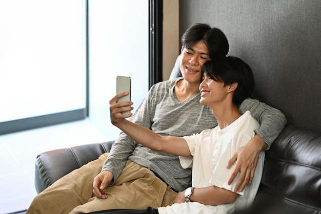 Loving male lgbt couple making selfie while relaxing on sofa at home