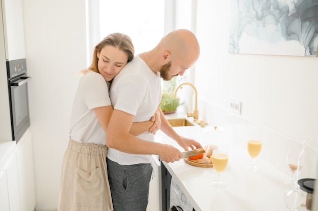 Loving man feeding happy woman showing care cooking healthy meal together on weekend