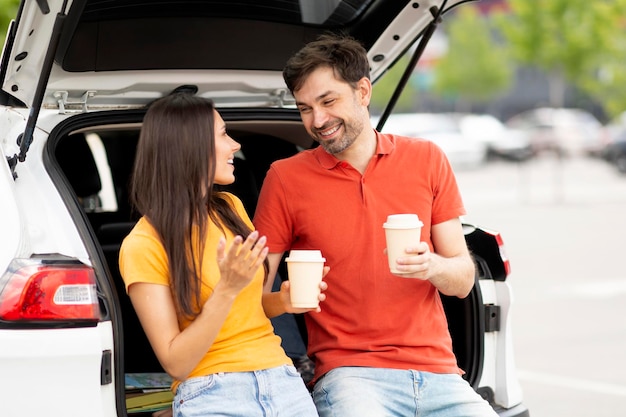 Loving millennial couple have break during road trip drinking coffee