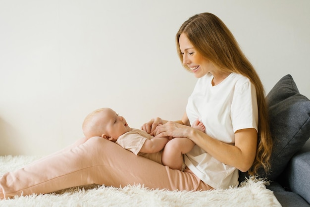 愛する母親は生まれたばかりの赤ちゃんを自宅で腕に抱き、ソファに座っている