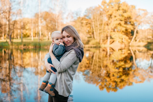 Loving mother hugs her child at nature with lake